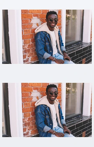 时尚微笑的非洲男子在牛仔裤夹克坐在城市街道, 砖墙背景