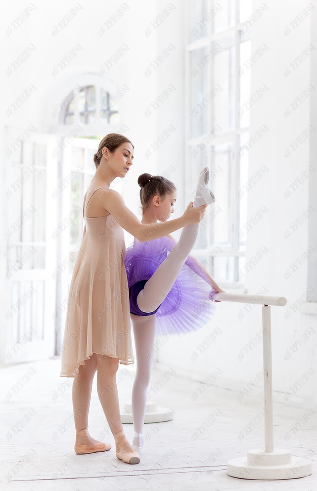 The little ballerina posing at ballet barre with personal teacher in dance studio