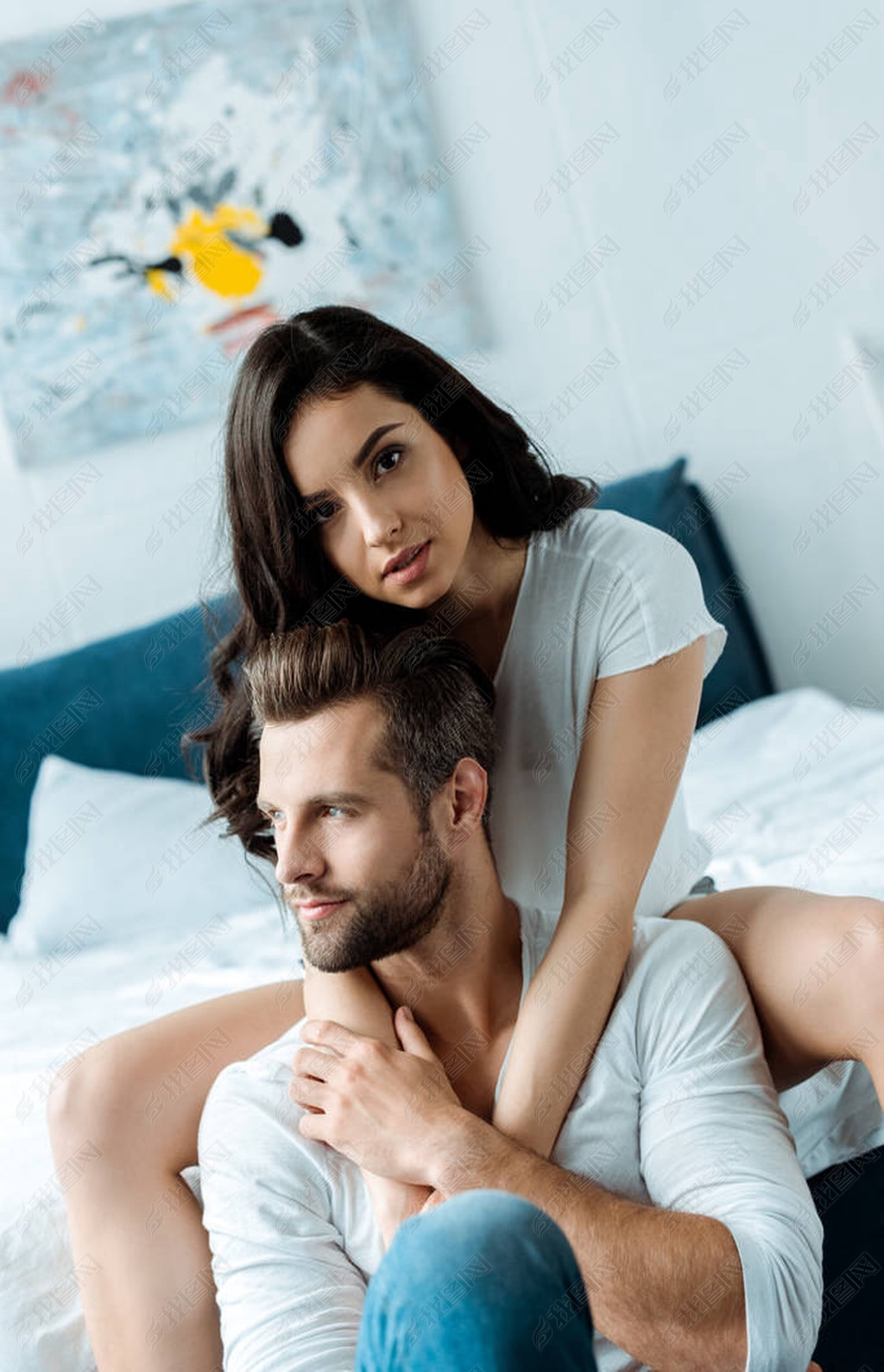 美丽的女人拥抱男朋友看着相机在卧室