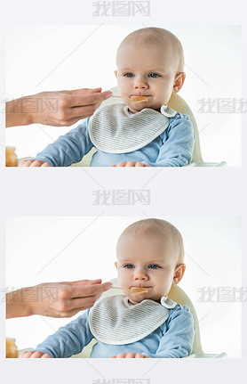 Selective focus of mom feeding adorable baby boy with fruit baby nutrition isolated on white