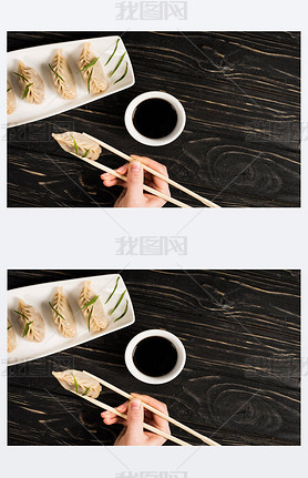 cropped view of woman eating delicious Chinese boiled dumpling with chopsticks and soy sauce at blac
