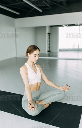  Exercises for self-control in yoga. Bright gym. Relaxed posture during meditation. The girl is sitt