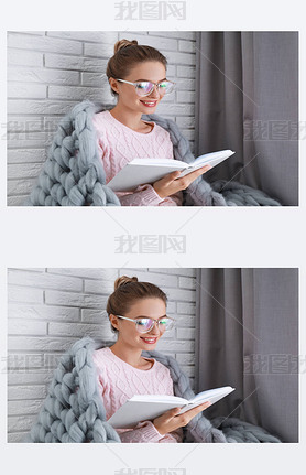 Young woman wearing knitted sweater with book at home