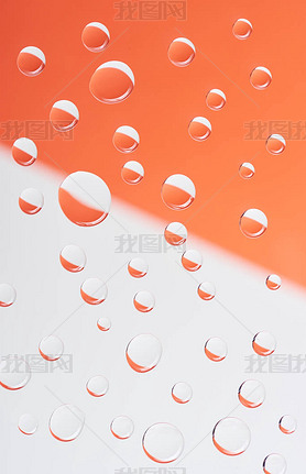 close-up view of transparent calm water drops on white and orange background          