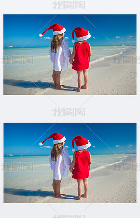Back view of Little cute girls?in Christmas hats on the exotic beach