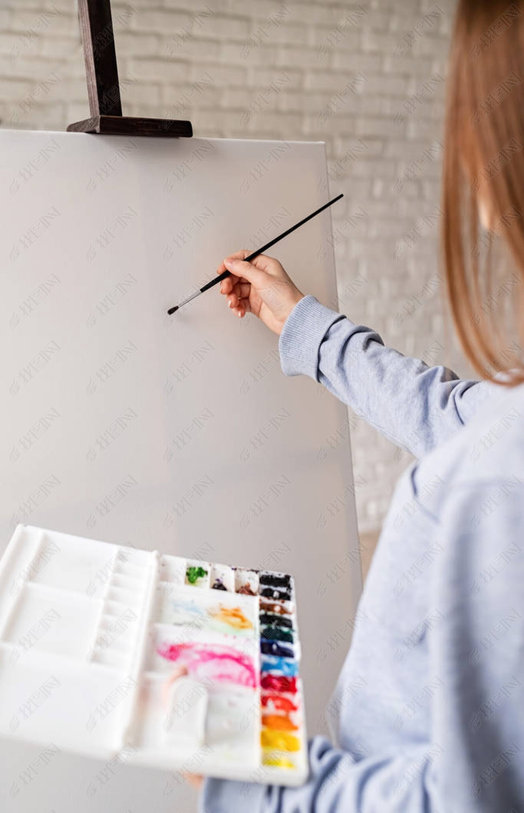 Female artist painting on the canvas in the studio