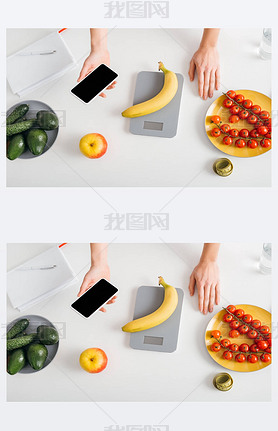 Top view of girl holding artphone while weighing banana on kitchen table, calorie counting diet