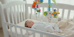 可爱的婴儿躺在摇篮与纺纱玩具旋转木马