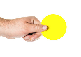 Mans hand holding a round yellow tablet