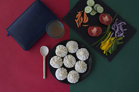 top view of khinkali, vegetables, juice, notepad, spoon on the table 