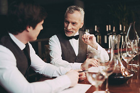 Experienced sommelier makes notes about taste qualities of wine drink sitting in restaurant.