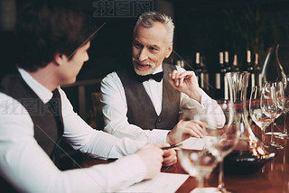 Experienced sommelier makes notes about taste qualities of wine drink sitting in restaurant.