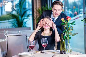 Surprise ahead. Romantic dinner in the restaurant. Young couple sitting at a table in the restaurant