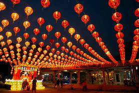 Red lanterns hanging in the black sky and god lamp at night in the Lantern Festival in Thailand.