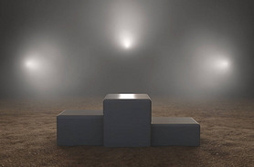 An empty classic winners podium on sand backlit by dramatic spot lights on a dark moody background -