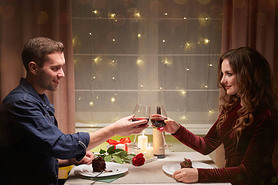 A loving couple drinks wine and eats dessert, celebrates Valentines day.