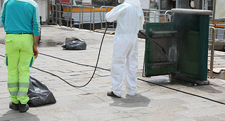 disinfestation of street furniture during the coronavirus epidemic with the worker in protective whi