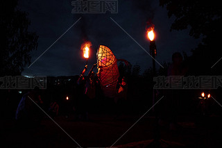 a dangerous and beautiful fireshow in the dark. artists in costumes of mythological creatures hold b