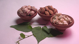 Assorted nuts with green leaves on studio background