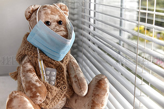 A teddy bear in a medical mask with pills and a thermometer