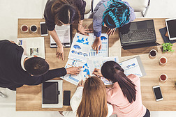 现代办公室：商人执行委员顶视图，在小组会议中与其他商人和女实业家一起，带着便携式计算机、咖啡和文件，为公司业务团队提供支持