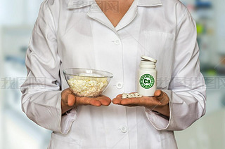 Young doctor holding curd and bottle of pills with vitamins and compare them