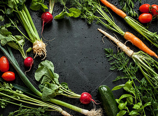 Young spring vegetables on black chalkboard