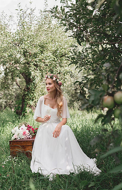 美丽快乐的年轻新娘捧着酒杯坐在花园里的老式胸前 