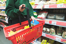女人把货物放在购物篮里。在超级市场购物。红色购物篮中的产品.