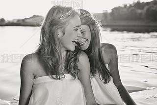 Black and white photography of 2 beautiful princess young ladies in white dresses on summer water ou