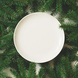 富有创意设计与白色背景上的空盘子的圣诞树枝做成。顶视图.