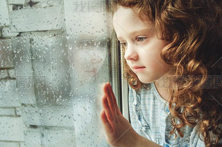 Sad child looking out the window. Toning photo.