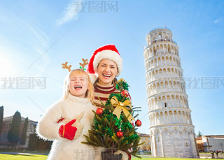 Happy woman and baby girl holding Christmas tree. Pisa, Italy