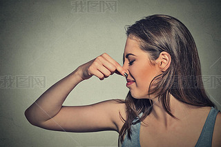 woman pinches nose with fingers looks with disgust away something stinks