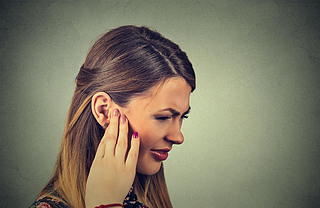 Tinnitus. Closeup side profile sick young woman hing ear pain touching her painful head
