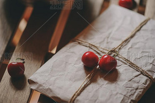 fresh cherries on plate with wrapped gift on wooden table. Vintage toned, farm life concept. Selecti