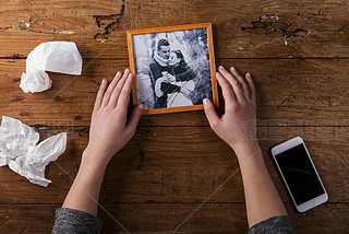 Unrecognizable sad woman holding broken picture of couple in love.