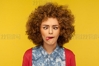 Closeup portrait of crazy woman with fluffy curly hair demonstrating tongue out and making silly fac