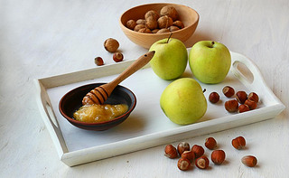 Apples, honey and nuts on a white tray