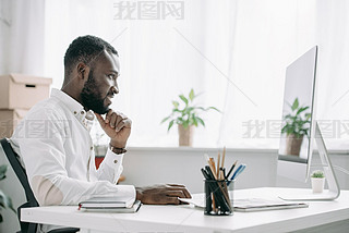 side view of cheerful handsome african american businesan working at computer in office