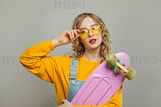 Pretty young woman with pink skateboard and sunglasses