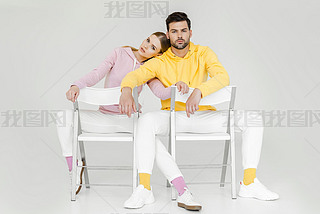 couple of models sitting on chairs and looking at camera on white