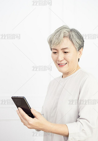 Happy mature senior asian woman holding artphone using mobile online apps.