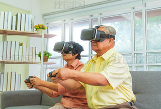 Senior Asian couple is playing Video game and wearing VR goggles for retirement technology lifestyle