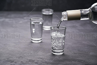 Pouring vodka into the glass on a black background, selective focus