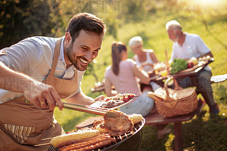 Summertime fun.Man cooking meat on barbecue for summer family lunch in the backyard of the house.