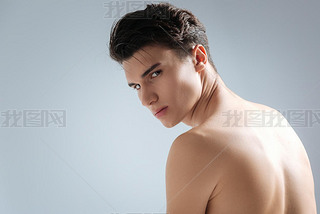 Naked young man sitting in studio