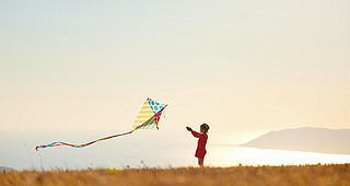 happy kid girl launches a kite at sunset outdoors