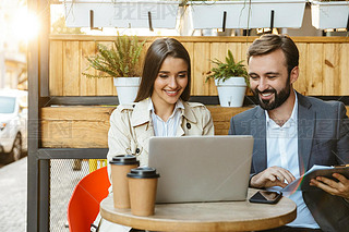 Portrait of pleased business couple man and woman hing conversation and working on laptop together