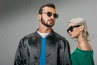 fashionable couple posing in sunglasses, isolated on grey